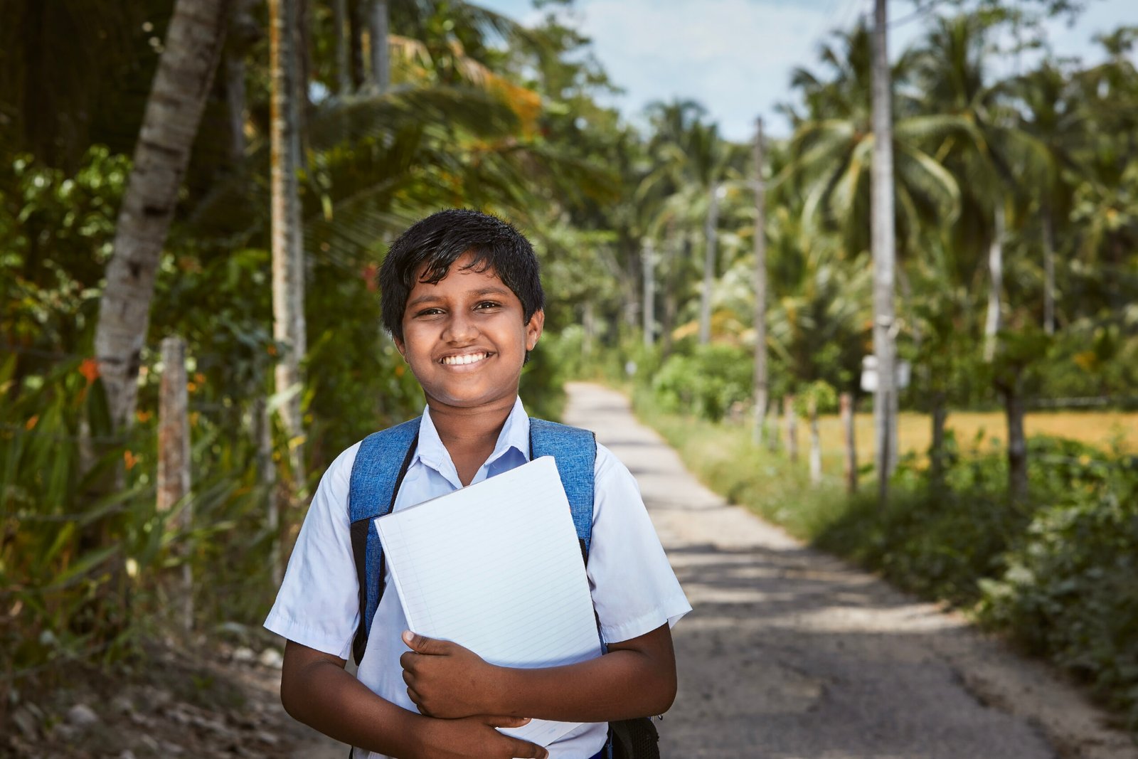 Schoolboy in uniform is walking to school. Portrait boy on rural road in Sri Lanka.